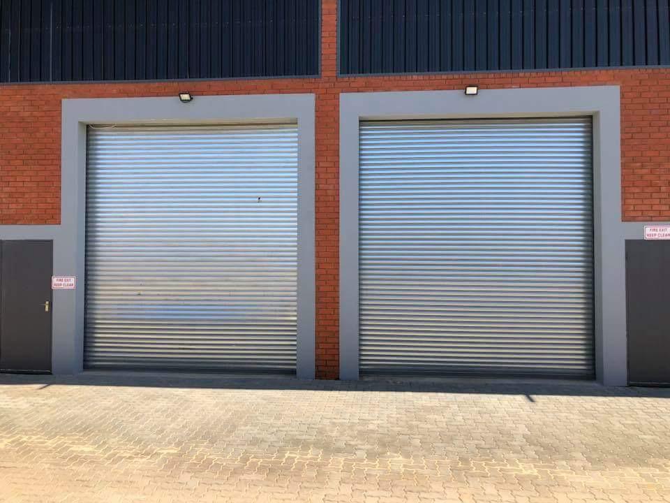 Two galvanized roller shutter doors installed in a brick commercial building