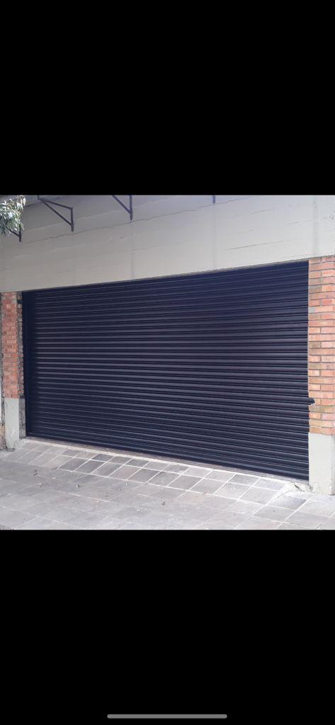 Navy powder-coated roller shutter door fitted to a brick building