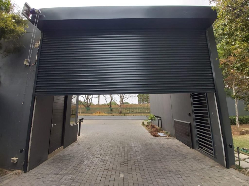 Dark powder-coated roller shutter door fitted to a covered carport opening